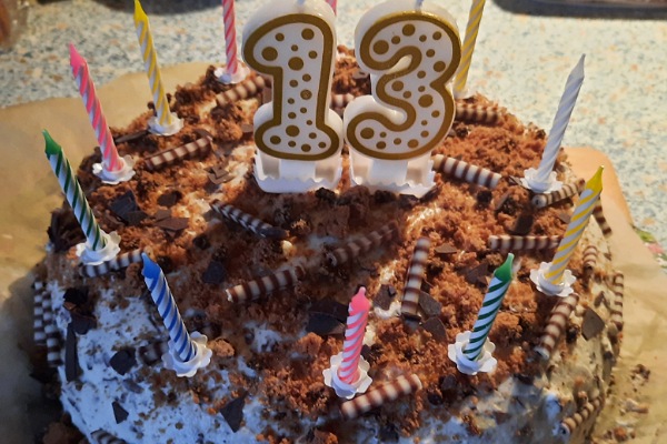 Eine Torte mit Kerzen und der Zahl 13 oben drauf.
